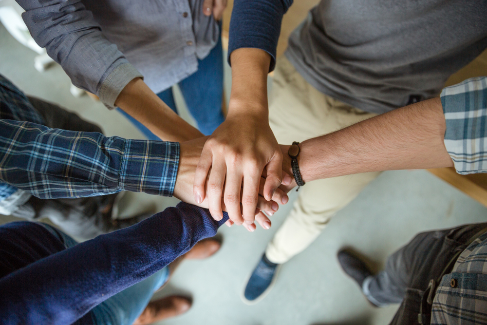 Top view of people joining hands together as a symbol of partnership